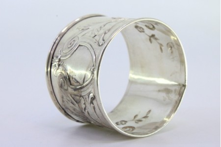  Argola de guardanapo em prata com motivos florais relevados e envolvendo cartela para monograma.